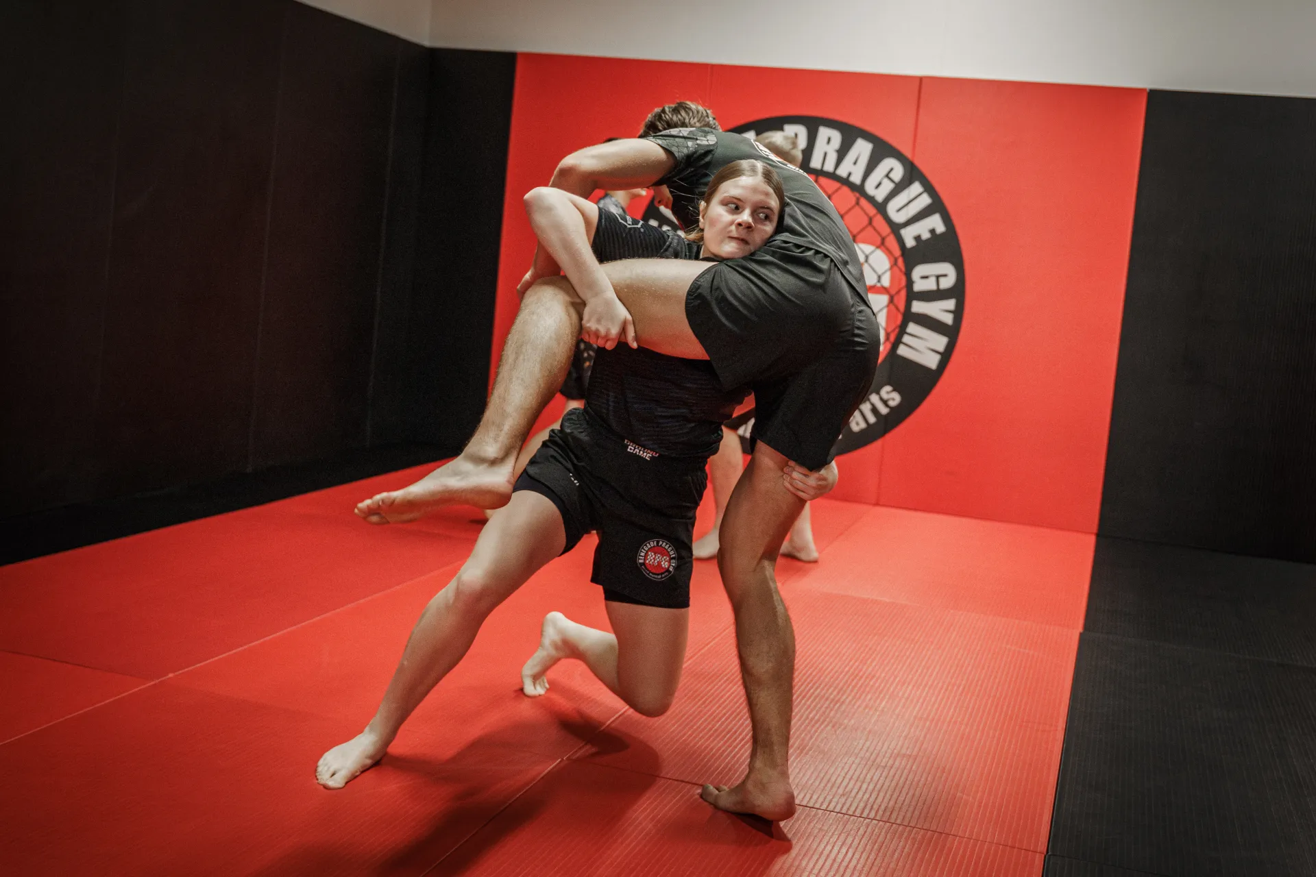 Juniorka provádí takedown a klinč na tatami